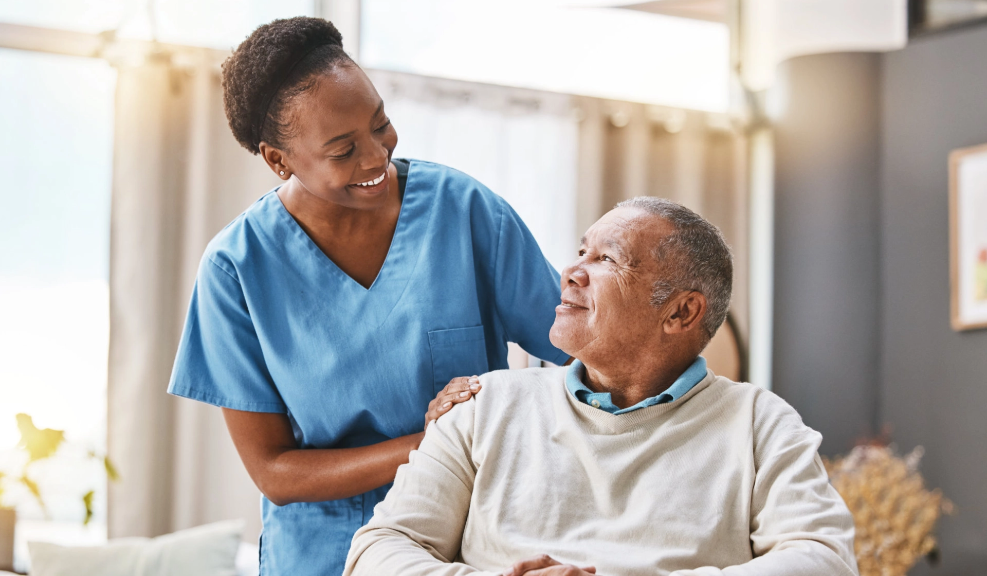 A female caregiver and an elderly man sittin on a wheelchair