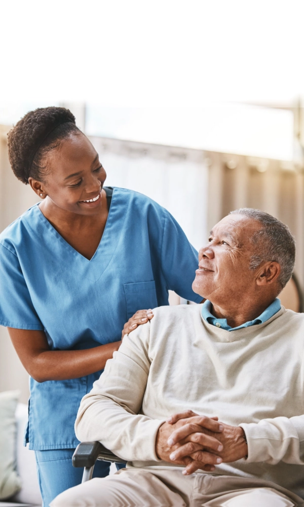 A female caregiver and an elderly man sittin on a wheelchair