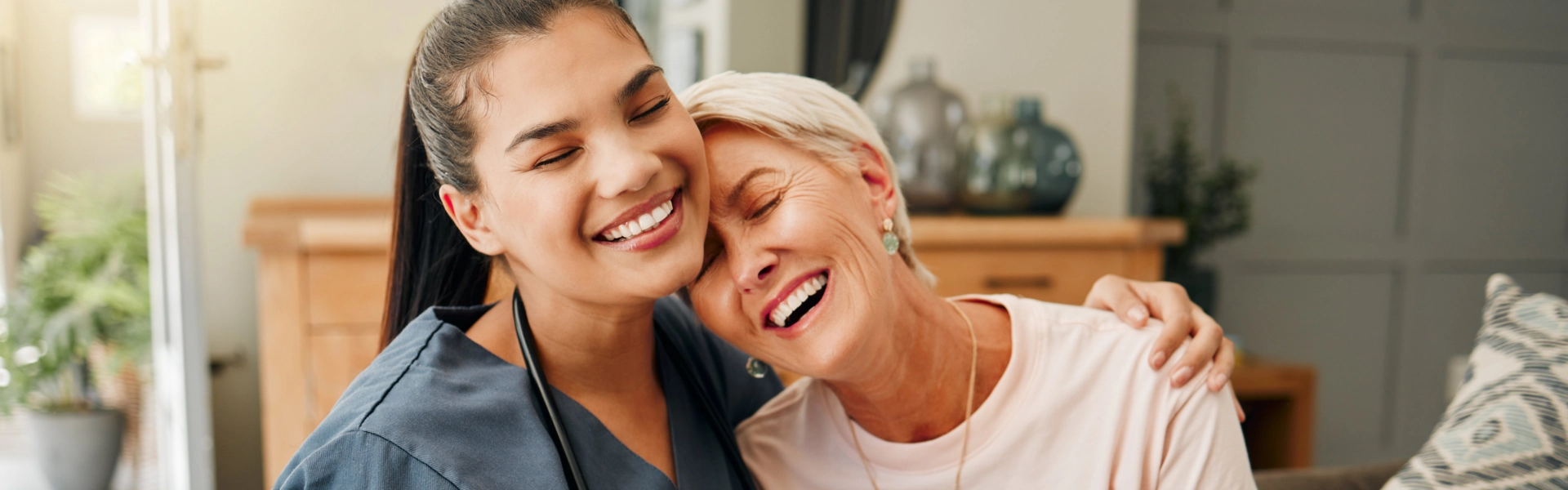 A female caregiver and an elderly woman hugging each other