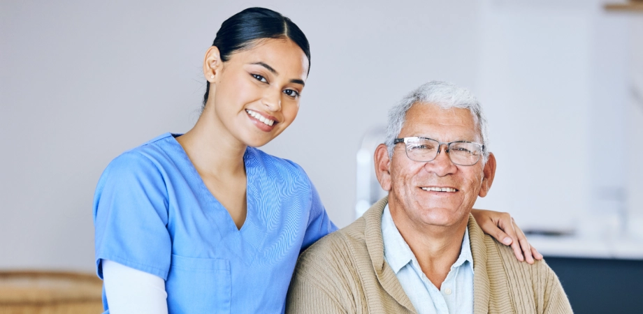 A female caregiver and an elderly man smiling together