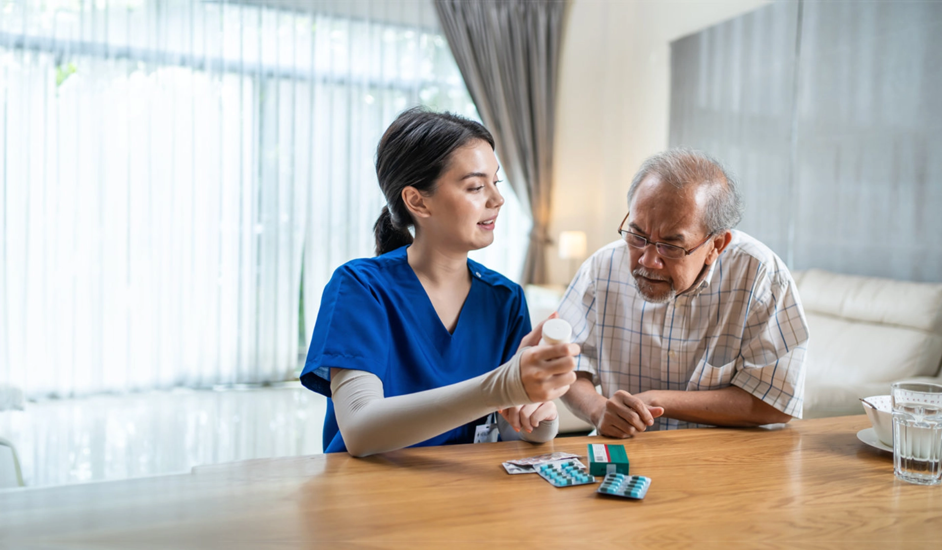 A female giving medication to an elderly man