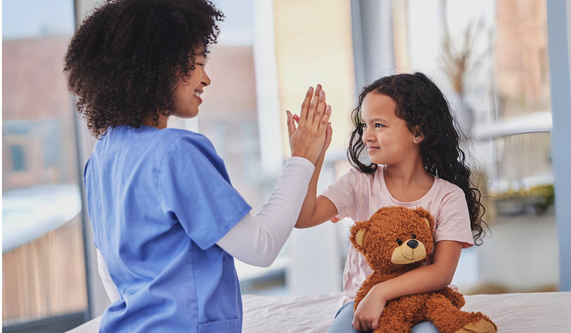 A female caregiver and a child do high five together