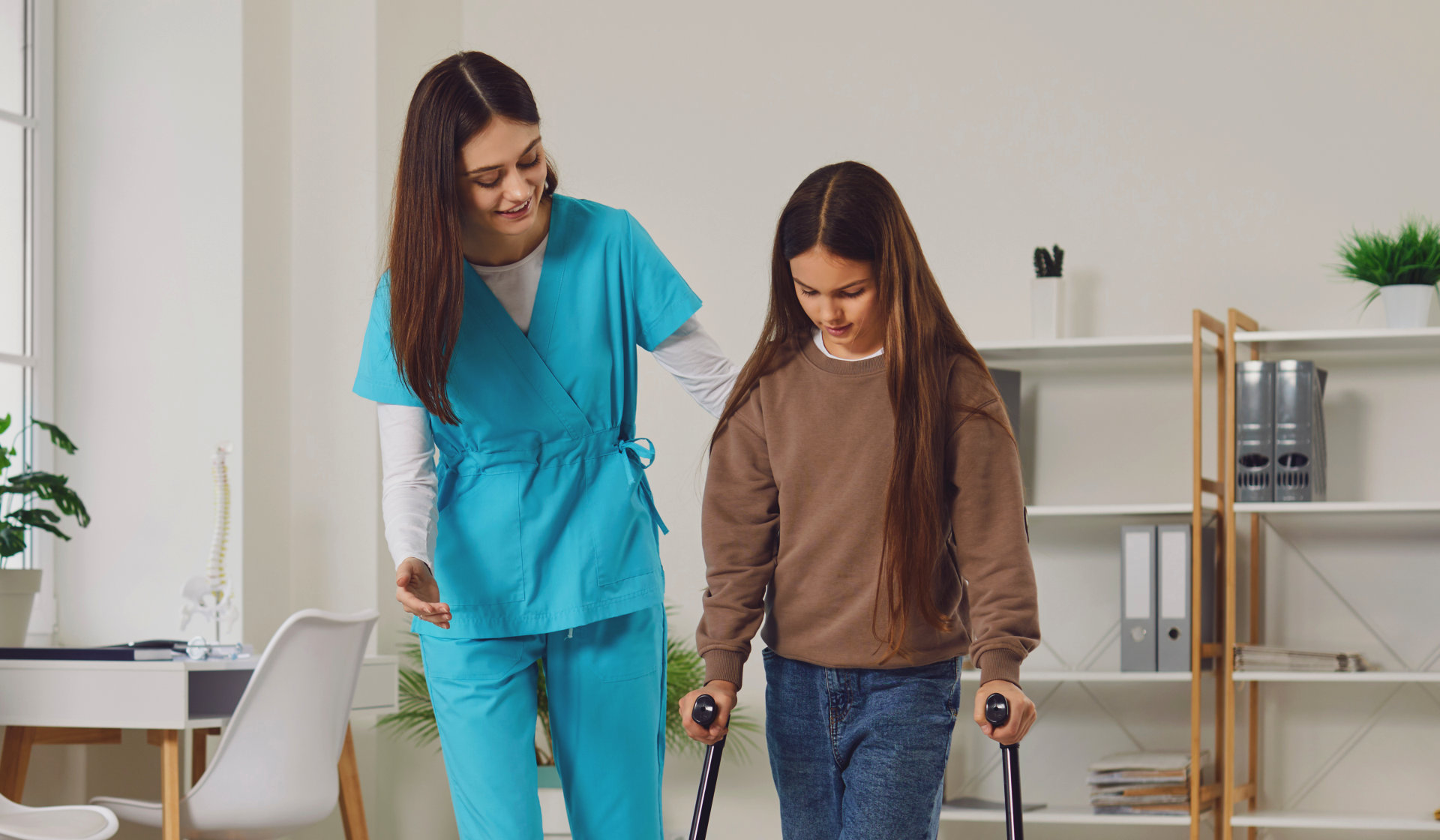 A female caregiver assisting a girl to walk