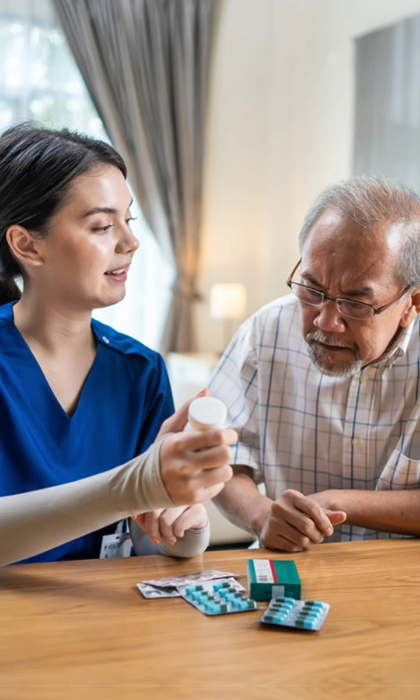 A female giving medication to an elderly man